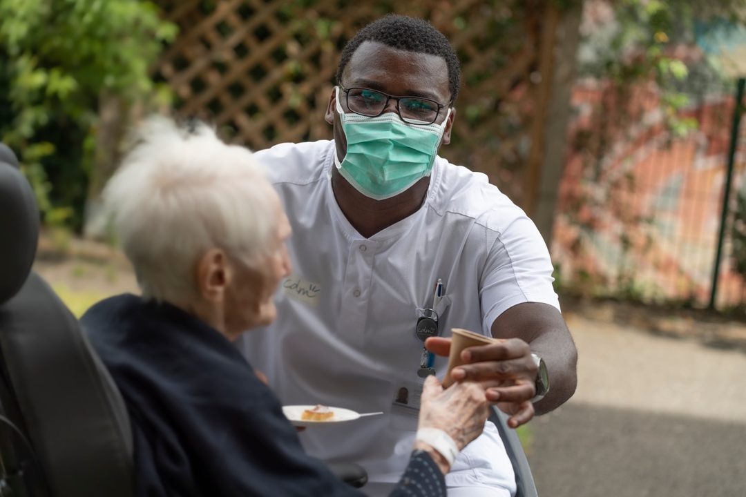 Photo illustrant un professionnel de santé de la clinique des minimes donnant un verre d'eau à une patiente